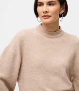 Suéter de punto color marrón chocolate, con cuello alto y mangas largas con puños ajustados. Presenta un diseño de corte corto y holgado.