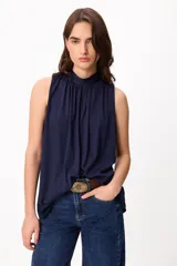 Blusa sin mangas de color azul marino, con cuello alto fruncido y caída fluida.