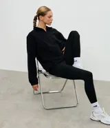 Buzo deportivo de fleece color crema, con cuello alto y cierre frontal parcial. Presenta mangas largas con puños elásticos y un diseño holgado con recortes frontales.