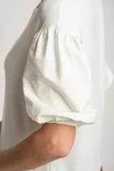 Remera blanca de manga corta abullonada con textura de puntos en relieve, escote redondo y calce holgado.