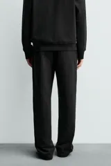 Pantalón jogger de corte regular fit y color negro, confeccionado en tejido compacto de algodón con interior de rizo. Cuenta con cintura elástica, bolsillos frontales y un bolsillo trasero de doble vivo.