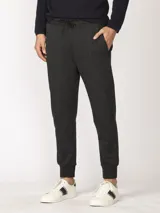 Pantalón jogging de corte slim en color gris oscuro jaspeado. Cuenta con cintura elástica con cordón ajustable, puños elásticos en los tobillos, bolsillos laterales con cierre y un bolsillo tipo parche.