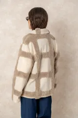 Chaqueta oversize con diseño de cuadros en relieve, confeccionada en una combinación de lana y poliéster con textura tipo borreguillo. Presenta un corte holgado, cuello con solapas y un botón joya central.