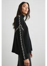 Sweater negro de punto con cuello alto y bordados blancos en sisas y mangas.