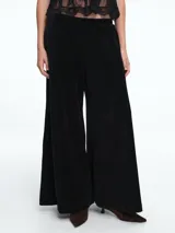 Pantalón de corte ancho y silueta relajada, confeccionado en tejido de pana negra con textura acanalada. Cuenta con cintura elástica y bolsillos laterales.