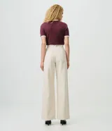 Pantalón wide leg de sarga color beige con estampado a rayas verticales oscuras, de cintura alta con pinzas frontales, bolsillos posteriores y calce amplio.