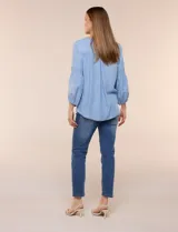 Blusa de tencel celeste con escote cuadrado, mangas tres cuartos abullonadas con puños elastizados y delicados bordados florales blancos en el frente y las mangas.