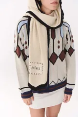 Bufanda de punto color marrón con capucha integrada y bordes en color crema. Presenta una etiqueta rectangular bordada con la palabra Anthea en uno de sus extremos.