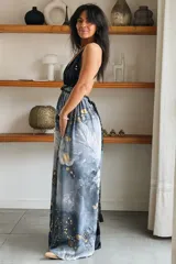 Vestido largo de seda con estampado abstracto en tonos marrones, beige y destellos dorados, con escote en V profundo, tirantes de cuerda anudados al cuello y la cintura, y tajo lateral en la falda.