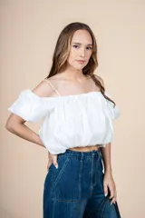 Blusa blanca con escote elástico que permite usarla con hombros descubiertos o más alta.