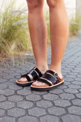 Sandalias bajas de cuero color marrón con tiras de cuero charol negro y hebilla metálica.