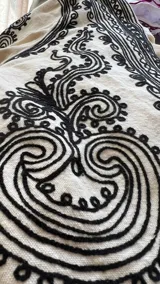 Chaqueta de algodón color crudo con bordados densos en tinta negra, de corte recto y mangas largas.