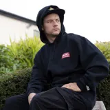 Canguro negro con capucha y bolsillo frontal. Estampado en el pecho con el logo de Independent en un recuadro rojo.