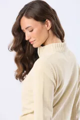 Buzo tejido combinado de color beige, con cuello alto, medio cierre metálico y puños y ruedo acanalados en tono tostado.