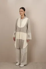 Camisa larga de lana fina sin teñir, con cuello mao y cierre frontal con un botón. Presenta un diseño de patchwork en tonos beige y gris con patrones de pata de gallo y texturas lineales. Las mangas son largas con tajo y detalle de botón en los puños.