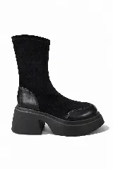 Bota corta de caña media confeccionada en una combinación de gamuza y cuero, con suela de plataforma robusta y taco cuadrado. Diseño minimalista en color negro.