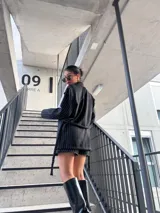 Blazer negro a rayas verticales blancas, con solapas de muesca, cierre cruzado con botones y corte entallado.