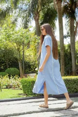 Vestido camisero midi celeste con botones frontales, cuello camisero, mangas cortas y detalles de ribetes amarillos.