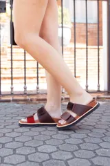 Sandalias de cuero color marrón con detalles en rojo, hechas a mano en Uruguay.