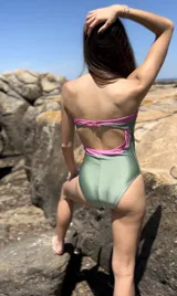 Traje de baño enterizo estilo strapless, con diseño bicolor que combina una franja superior en color rosado y el cuerpo principal en color verde oliva.