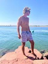 Short de baño con estampado floral en tonos azules y rosados, confeccionado en tela de secado rápido. Cuenta con cintura elástica, dos bolsillos laterales, un bolsillo trasero y malla interior hipoalergénica.