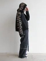 Hoodie con cierre frontal, confeccionado en tejido de punto 100% algodón. Es una prenda reversible con diseño de estampado gráfico en mangas y capucha, y presenta detalles de roturas intencionales en puños, ruedo y bolsillos.