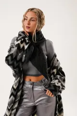 Bufanda negra con diseño capitoné acolchado y costuras decorativas. Presenta una terminación en pico y un sistema de ajuste mediante una tira integrada para cruzarla.