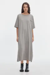 Vestido midi gris con efecto washed, cuello redondo, manga corta, corte recto y holgado, con pequeños tajos laterales en el bajo y un parche bordado en el pecho.