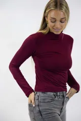Polera color beige de manga larga y cuello alto, confeccionada en tejido ajustado al cuerpo.