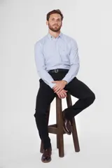 Pantalón de gabardina color marrón claro, corte slim fit, con bolsillos laterales y traseros. Se ajusta a la cintura con cinturón de cuero marrón.