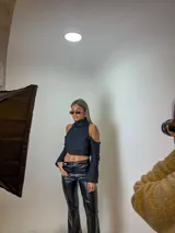 Blusa corta negra con cuello alto, hombros descubiertos y mangas largas.