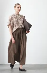 Falda larga plisada color marrón, de silueta amplia y caída fluida.