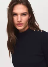Jersey de punto fino en color azul marino, con cuello perkins y cierre de botones decorativos efecto joya en el hombro. Presenta un diseño recto de manga larga con detalles de ribetes en tono contrastante.