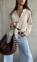 Camisa de manga larga color beige con diseño abotonado frontal, cuello mao y detalles de bordados y encaje en el frente y las mangas.
