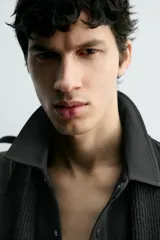 Sobrecamisa de corte regular fit en tejido elástico y transpirable, con cuello solapa, cierre frontal mediante botones a presión y bolsillo de plastrón en el pecho. Presenta mangas largas con puños abotonados y bajo con aberturas laterales.