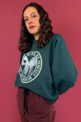 Buzo verde oscuro de friza de algodón con cuello redondo y mangas raglán. Estampa circular en el frente con la frase "Be Real Not Perfect" y un moño blanco.