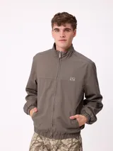 Campera Rusty de corte clásico, color negro, con cierre frontal completo, cuello alto y puños elásticos. Presenta un diseño minimalista con el logo de la marca bordado en el pecho.