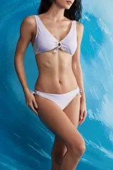 Conjunto de bikini de dos piezas en color lila con estampado en tonos amarillos. El top presenta un diseño de bralette con escote en V, un aro decorativo en el centro y lazo frontal. La bombacha es de corte colaless con tiras ajustables en los laterales.