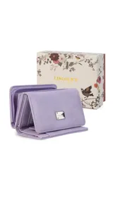 Billetera corta de símil cuero color beige, con cierre a presión y placa metálica decorativa. Cuenta con múltiples compartimentos internos para tarjetas, visor y billetes, además de un compartimento posterior con cierre.