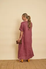 Vestido tipo túnica largo de lino, color bordo, con mangas cortas, bolsillos laterales y detalle de volados en la botonera frontal.