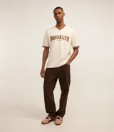 Pantalón de corte baggy confeccionado en sarga de algodón, con cintura fija, trabillas para cinturón, cierre de cremallera y bolsillos laterales y traseros.