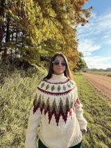 Sweater de lana color crema con cuello alto y diseño geométrico en tonos verde y bordó. Tejido a mano.