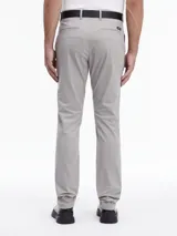 Pantalón chino de sarga elástica, color gris claro, de corte slim y talle medio. Incluye un cinturón negro con hebilla en forma de D.