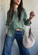 Camisa de manga larga color verde militar, con cuello camisero, cierre frontal de botones y detalles de bordados y calados en el frente y las mangas.