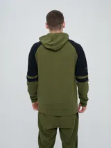 Campera canguro deportiva Umbro para hombre, de color verde militar con mangas negras de diseño raglán y detalles en verde militar. Cuenta con cierre frontal completo, capucha con cordones ajustables y bolsillos estilo canguro.