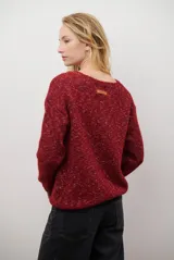 Buzo de punto color gris claro con motas oscuras, escote en V y mangas largas.