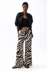 Pantalón largo de corte holgado y piernas amplias con estampado animal print de cebra. Cuenta con tiro alto, cintura elástica y cordón ajustable.
