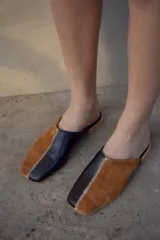 Mules con capellada dividida en cuero de oveja negro y gamuza color camel. Forradas en cuero, con base ultraliviana y taco de 1.5 cm.