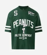 Remera de corte boxy y estilo deportivo, color verde oscuro, con diseño inspirado en el fútbol americano de Peanuts. Presenta cuello redondo, mangas cortas con franjas blancas horizontales y estampas localizadas de Snoopy en el frente.