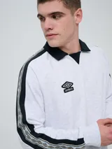 Buzo deportivo Umbro modelo Mixtape, color negro con cuello polo blanco y franjas blancas en las mangas con logo de la marca. Cuenta con puños y cintura elastizados.